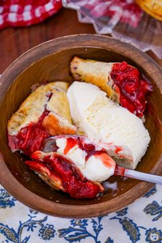 a wooden bowl filled with ice cream and strawberry shortcakes on top of a table