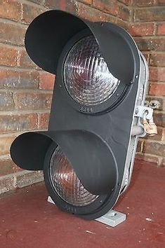 two traffic lights sitting next to each other on the ground near a brick wall and floor