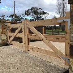 a wooden gate that is open on the side of a stone wall and gravel ground