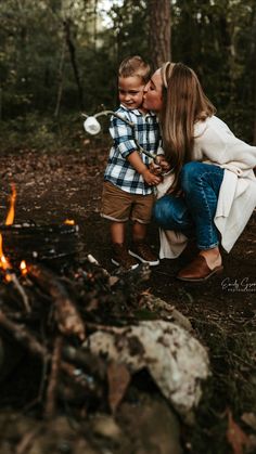 a woman kissing a young boy in front of a campfire