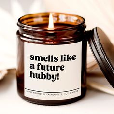 a candle that is sitting next to a book with the words smells like a future hubby on it