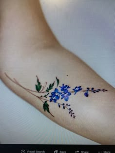 the arm is covered with blue flowers and green leaves, as if it were painted on