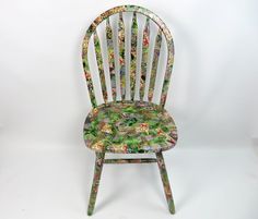 a wooden chair with floral fabric on it's back and seat, against a white background