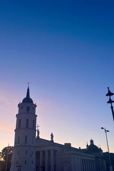 the sun is setting in front of a large building with two towers and a clock tower