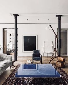 a living room with white walls and blue glass coffee table in front of the couch