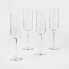 four empty wine glasses lined up on a white surface