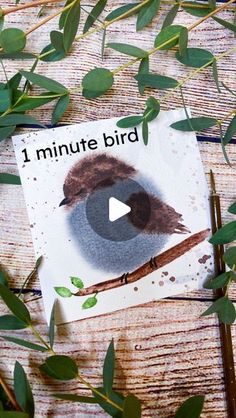 a bird sitting on top of a piece of paper next to green leaves and twigs