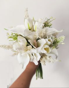 a hand holding a bouquet of white flowers