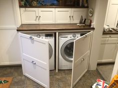 two washers are in the middle of a kitchen with white cupboards and drawers