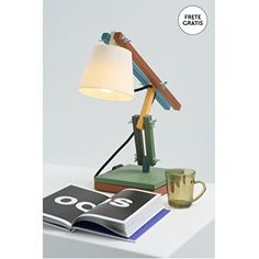 a table lamp with a book and coffee cup on it next to an open magazine