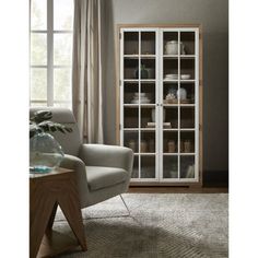 a living room scene with focus on the chair and bookcase against the wall in front of the window