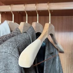 clothes hanging on wooden hangers in a closet