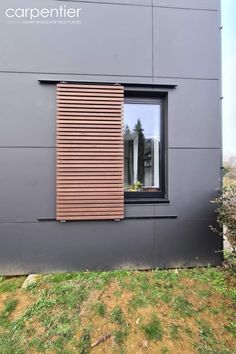 the side of a building with a window and wooden slatted shutters on it