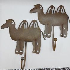 two metal camel hooks hang on the wall