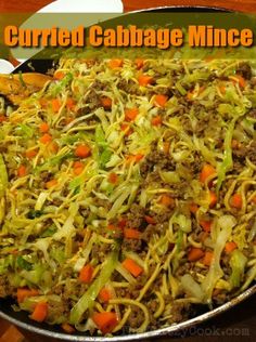 a pan filled with shredded cabbage and carrots next to a plate of food on a table