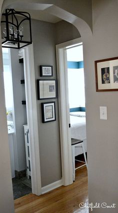 an open door leading to a bedroom with a bed in the corner and pictures on the wall