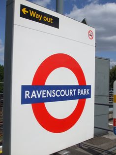 a sign that says ravennescourt park on it's side next to a train track