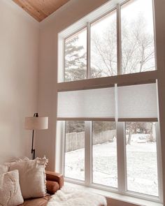 a living room filled with furniture and windows covered in white blinds on top of them