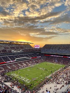 a football stadium filled with lots of people watching the sun go down over the field