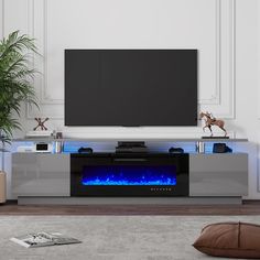 an entertainment center with a large television and blue flames on the side, in front of a wall mounted flat screen tv