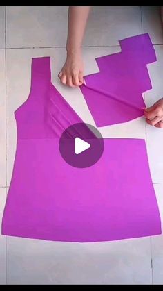 someone is making a dress out of purple material on the floor with scissors and tape