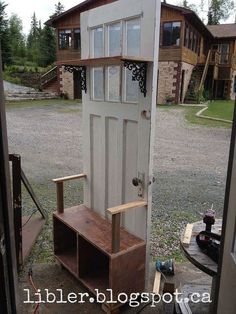 an old door is opened to reveal a wooden bench and shelf in front of it