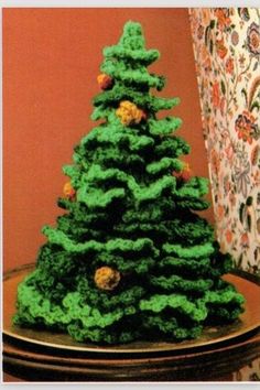 a green crocheted christmas tree sitting on top of a table next to a window