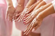 four bridesmaids holding their hands together with rings on each hand and bracelets on the other