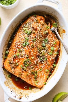 salmon with sesame seeds and green onions in a white casserole dish on a table