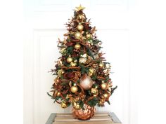 a small christmas tree with gold and silver ornaments on it's top, in front of a white door