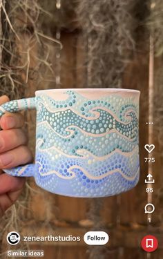 a hand holding a blue and white coffee mug