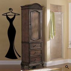 a tall wooden armoire sitting next to a bathroom sink and shower stall in front of a wall with a black dress on it