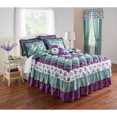 a bed with purple, green and white bedspread in front of a window