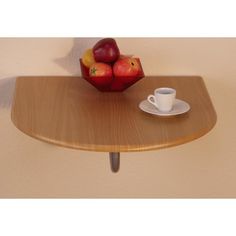 a wooden table topped with a cup of coffee and two apples on top of it