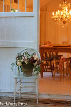 a potted plant sitting on top of a chair next to a table and chandelier