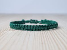 a close up of a green bracelet on a wooden table with white wall in the background