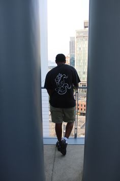 a man standing on top of a tall building looking out at the city from his balcony