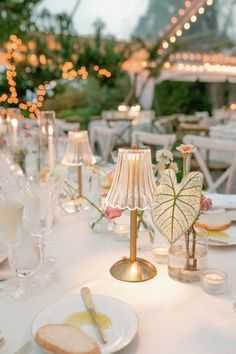 the table is set with white linens and gold chargers, candles, and glassware