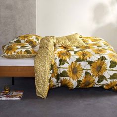 a bed with yellow sunflowers on it in a white room next to a wall