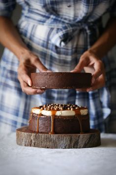 a person holding a piece of cake on top of a wooden platter next to another plate