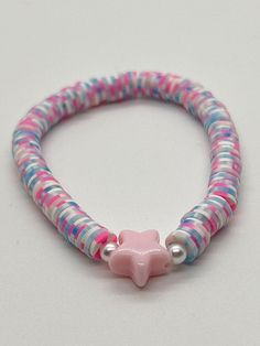 a close up of a bracelet on a white surface with a pink star charm attached to it