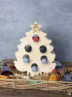 a wooden christmas tree sitting in a basket filled with nuts and other things to make it look like an ornament