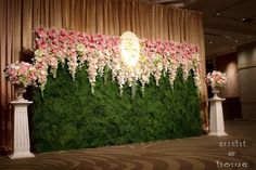 an arrangement of flowers and greenery in front of a backdrop at a wedding reception