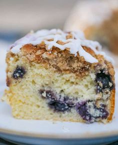 a close up of a piece of cake on a plate with icing and blueberries