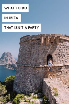 a woman sitting on top of a stone tower next to the ocean with text overlay that reads what to do in ibiza that isn't a party