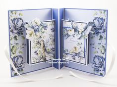 an open card with blue flowers and white ribbon on the inside, in front of a white background