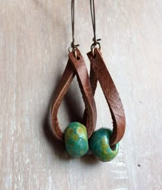 two small beads are hanging from brown leather earrings