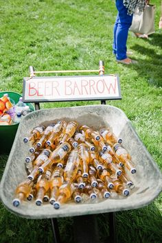 there are many beer bottles that are in the tray on the table and people standing around