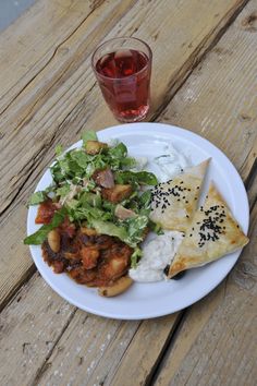 a white plate topped with food next to a cup of tea on top of a wooden table