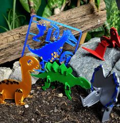 four metal dinosaurs are sitting in the dirt